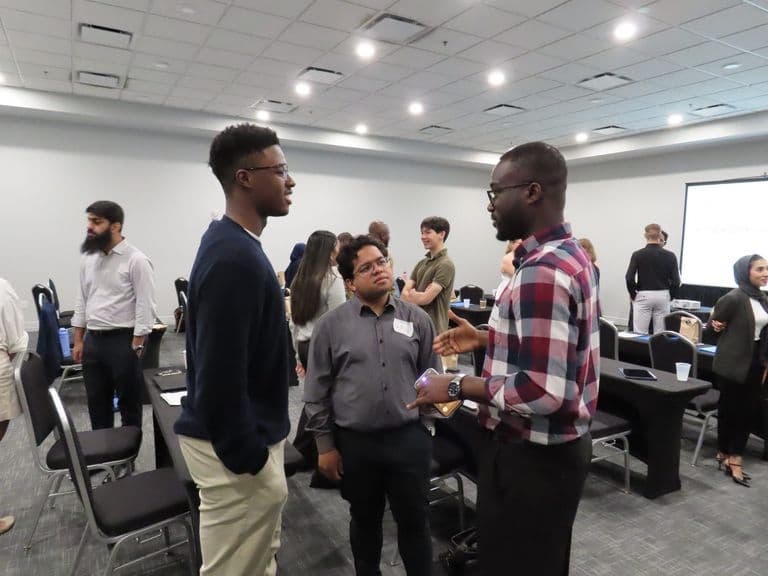 three men standing and speaking to each other