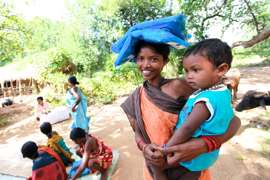 woman holding a baby with a mosquito net package on her head